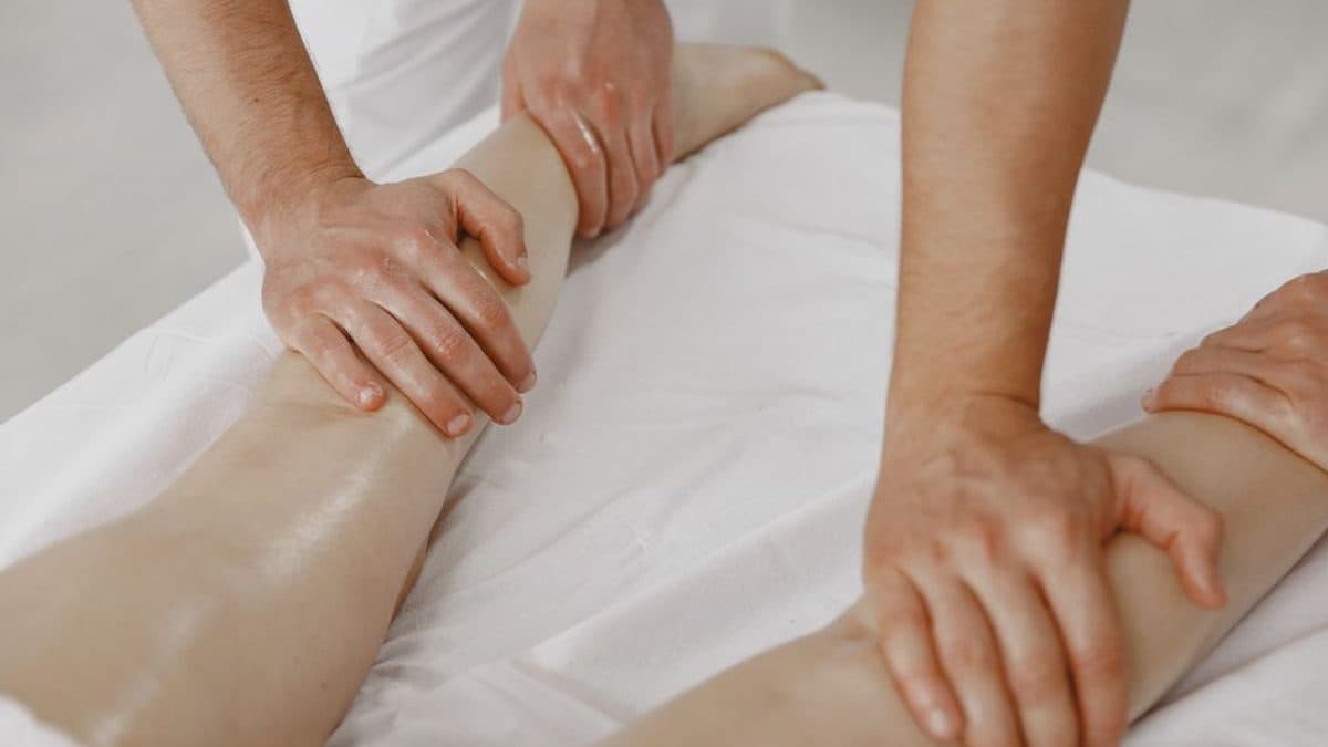 Mains d'une thérapeute glissant lentement le long de l'avant-bras d'une patiente allongée