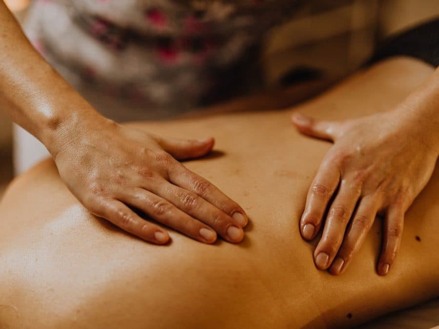 Mains posées à plat sur le dos d'une personne, lors d'un massage à l'huile